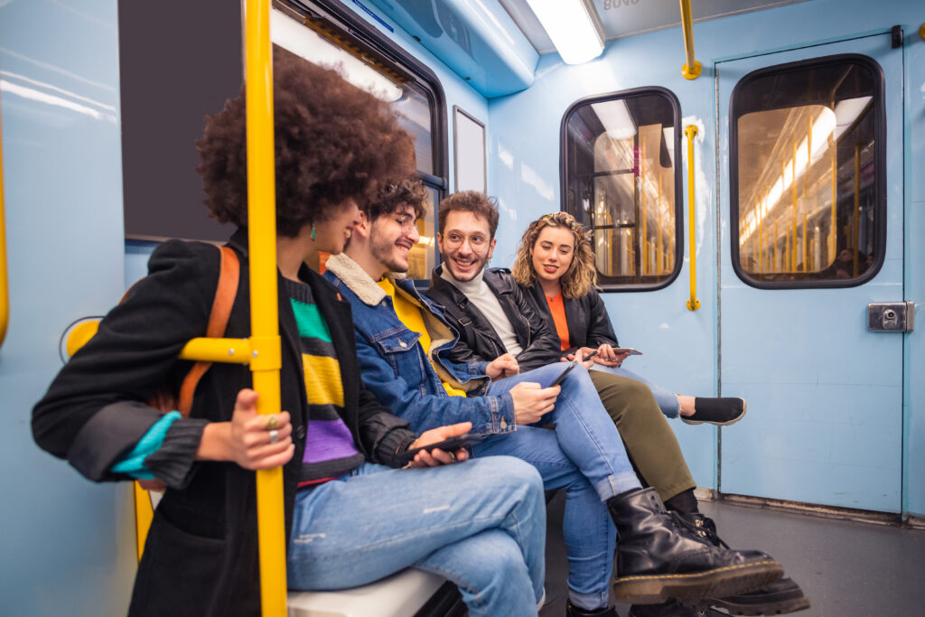 Group of four multiethnic people traveling subway using smartphone - Group of friends multiracial talking together using smartphone - technology, commute, togetherness concept